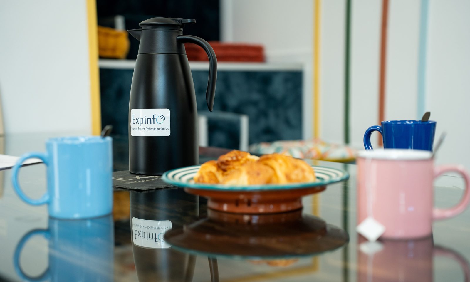 Mug aux couleurs d'Expinfo pos&eacute; sur un bureau